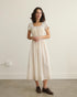 Theodosia Dress — romantic cream cotton gauze midi with lace trim, puff sleeves, and tie-back sash, ethically made in India.