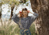 Woman in a black checkered vintage inspired blouse standing next to a tree in a natural setting