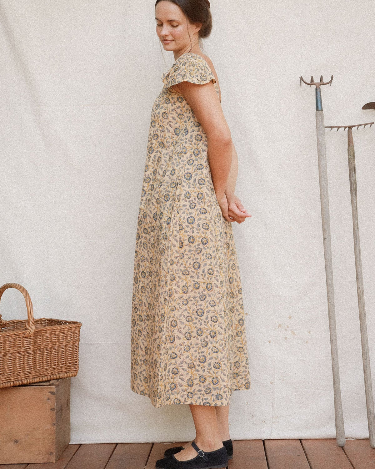 A woman wears the Lia Dress in Terrasse hand block floral cotton with gathered scoop neckline