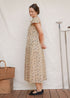 A woman wears the Lia Dress in Terrasse hand block floral cotton with gathered scoop neckline