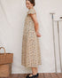 A woman wears the Lia Dress in Terrasse hand block floral cotton with gathered scoop neckline